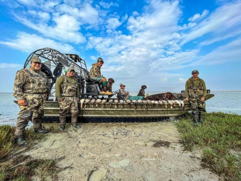 Hunters with their ducks on the shore