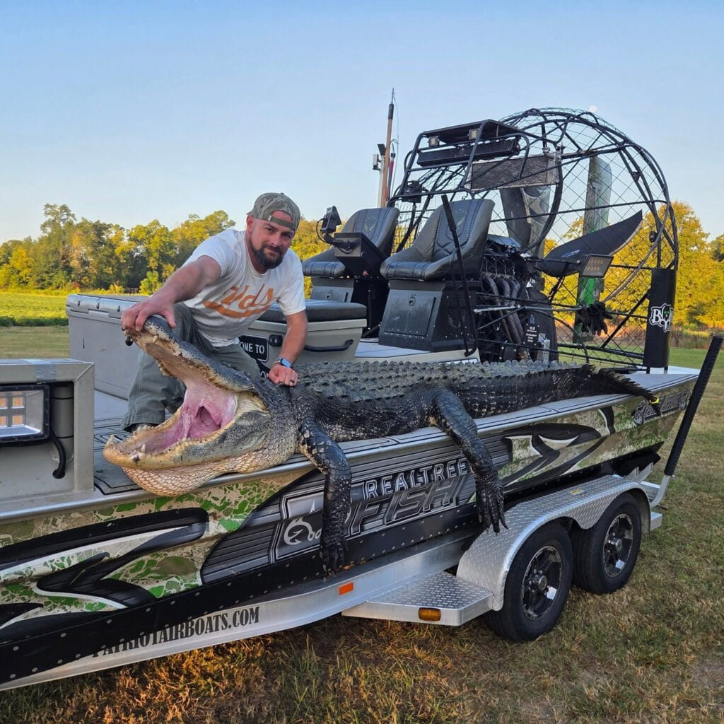 A hunter with a big alligator on a Patriot airboat at the trailer