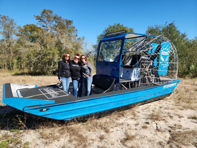 A blue cabin airboat and its owners on the sand
