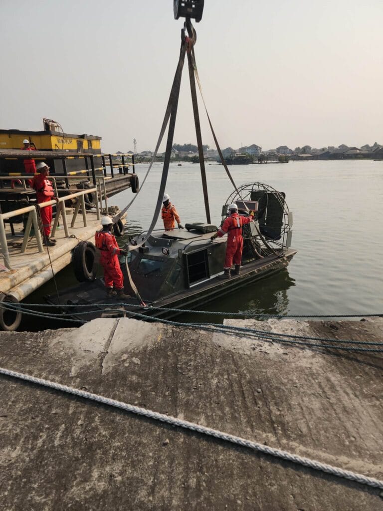 A military airboat lowered into the water by crane