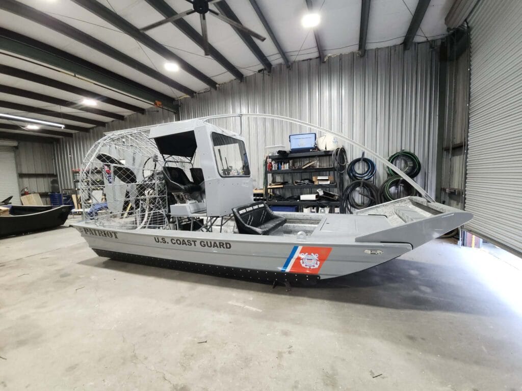 Airboat maintenance: a Patriot airboat inside the shop bay, with hoses and tools along the wall
