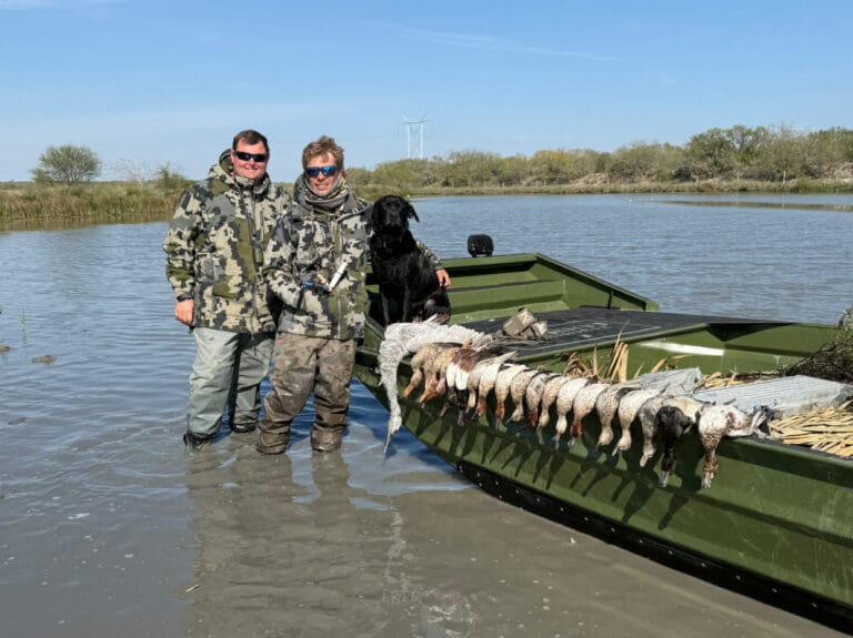 Two hunters, a lab and the day's ducks on a green Patriot