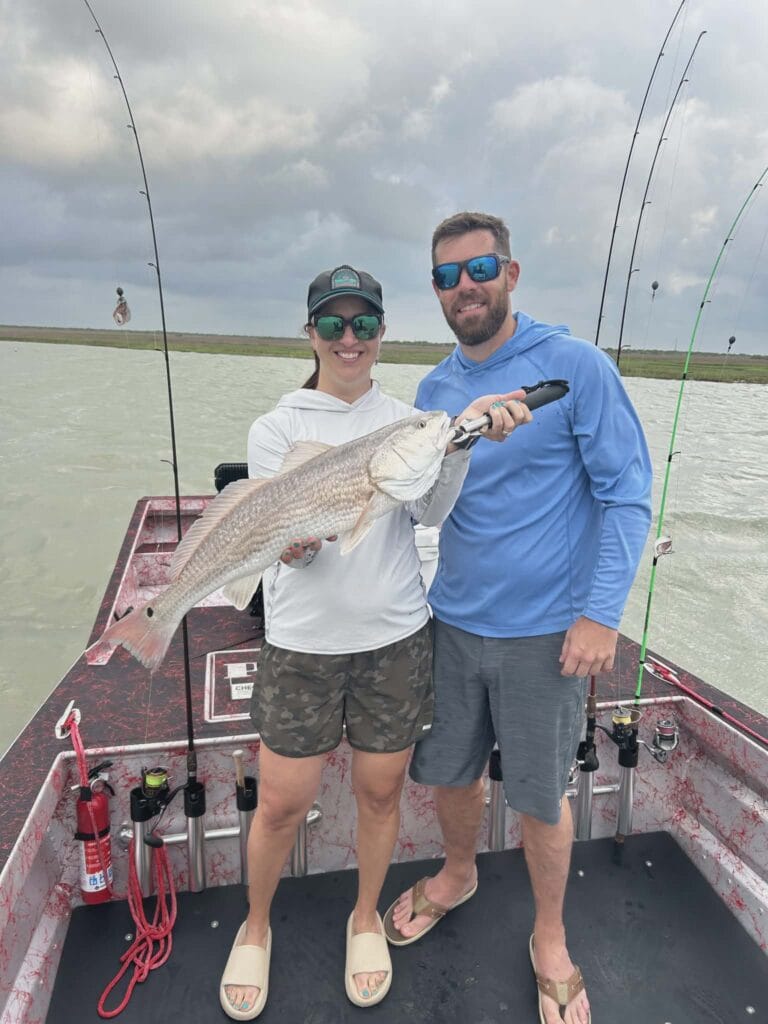 A couple holding a fish caught off a Patriot