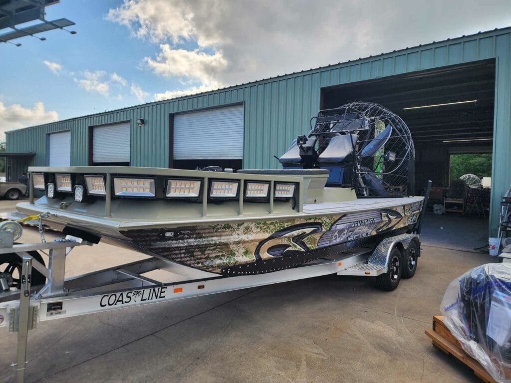Airboat on its trailer outside the open bay door of the Patriot Airboats shop in Vidor, Texas