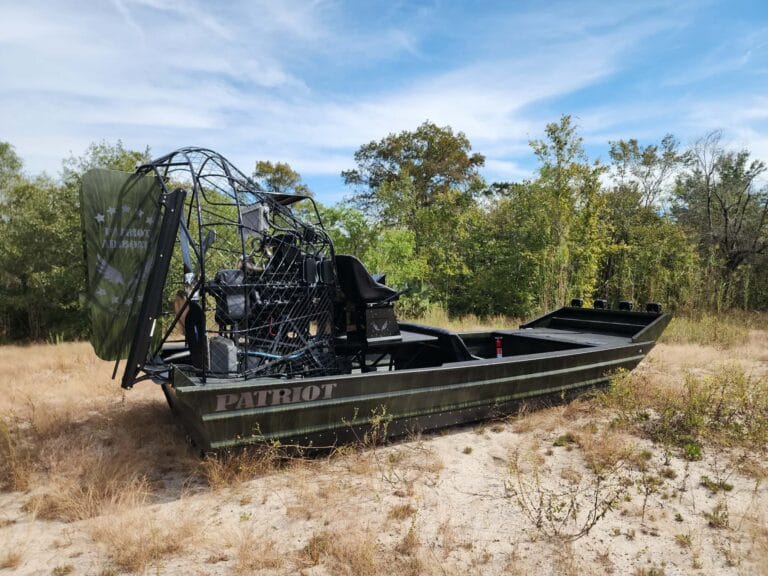 A camo airboat parked on dry ground
