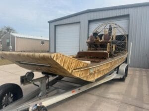 2019 AirRanger airboat on its trailer outside a metal shop building, bow quarter
