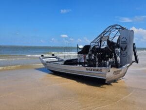 2023 Patriot airboat beached in the surf on a sandy shore