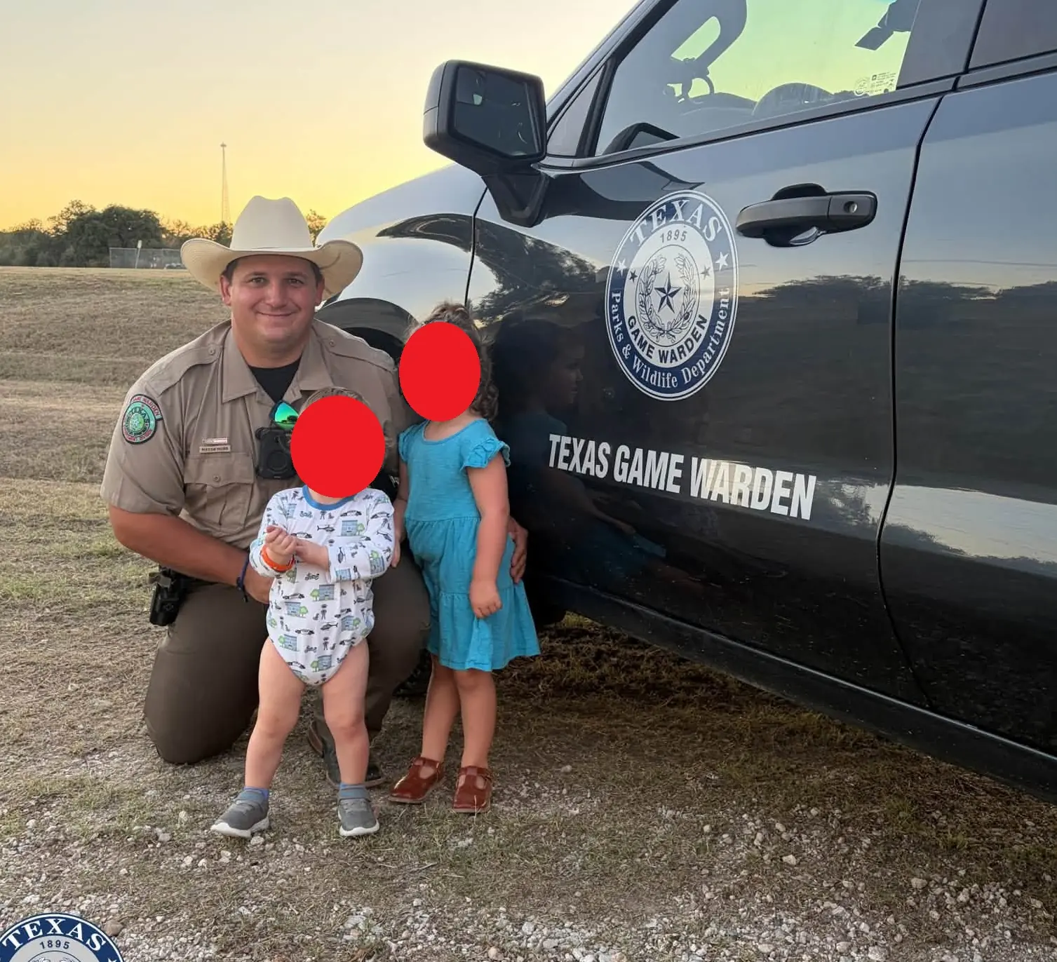 A Texas Game Warden meeting visitors beside a marked Texas Game Warden truck at sunset