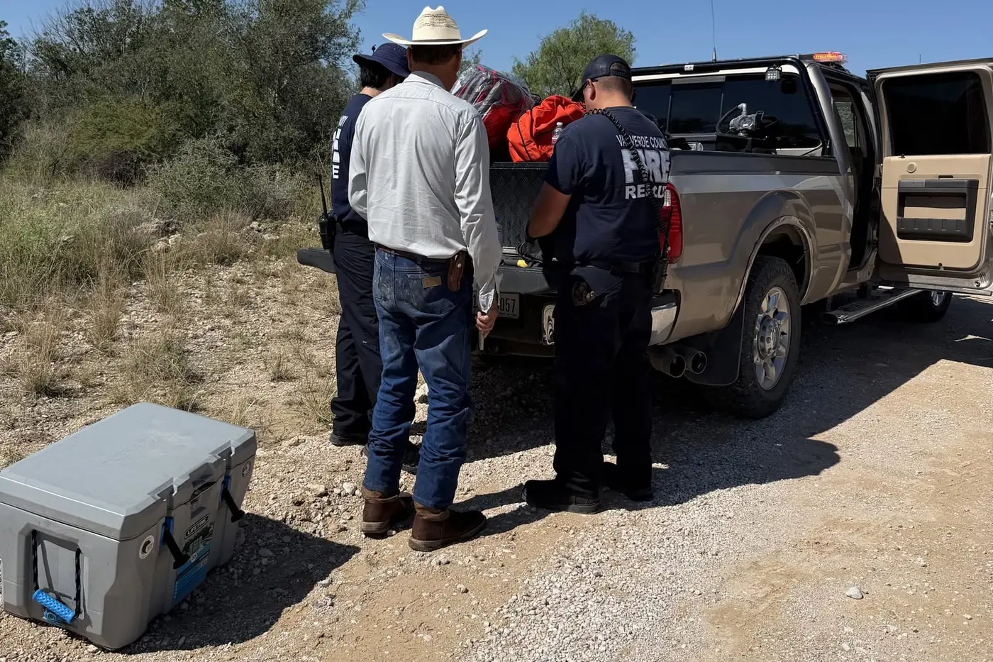 Val Verde County Fire Rescue crew pulling rescue gear from a pickup bed near the Dolan Creek Road crossing